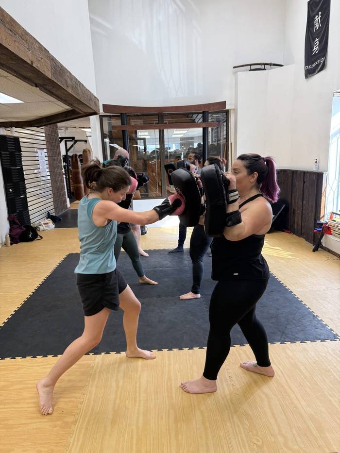 Kickboxing bootcamp members doing pad drills in class